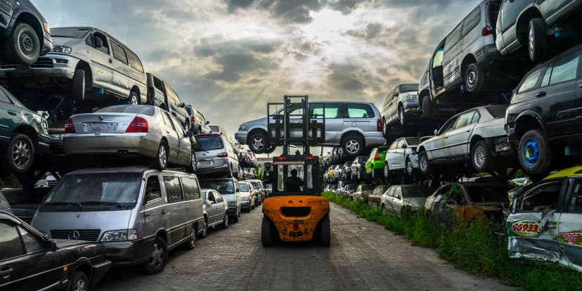 Une voiture épave recyclée transportée par un chariot élévateur